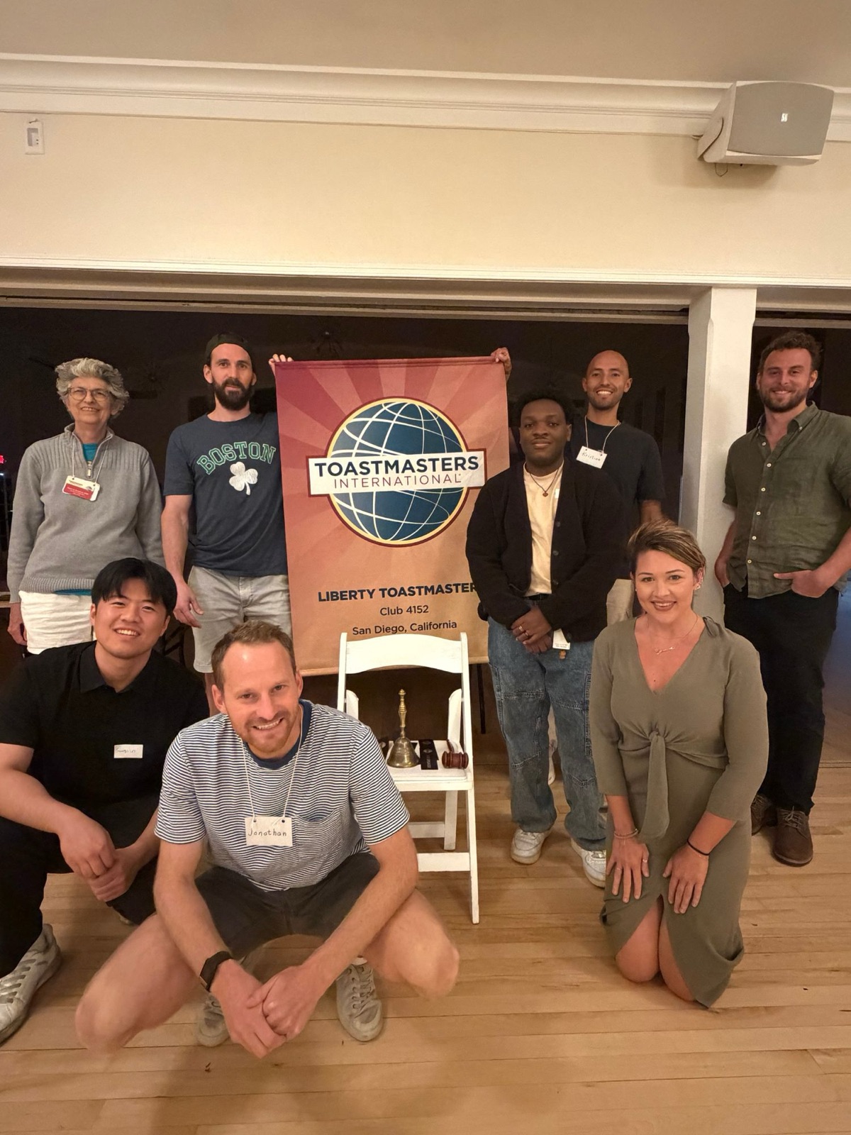 Liberty Toastmasters members standing around the club banner after a meeting